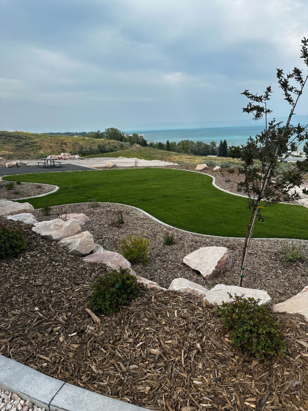 Concrete landscape curbing around mulch bed with boulders and Utah lake view